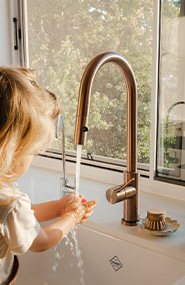 Child washing hands at kitchen tap