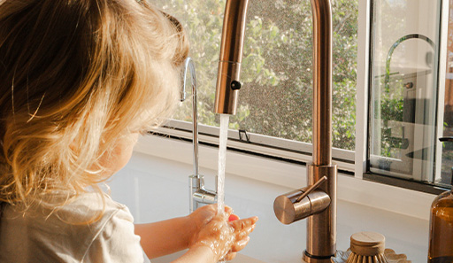 Child washing hands at kitchen tap